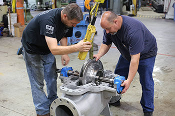 two men performing repair services on a pump.